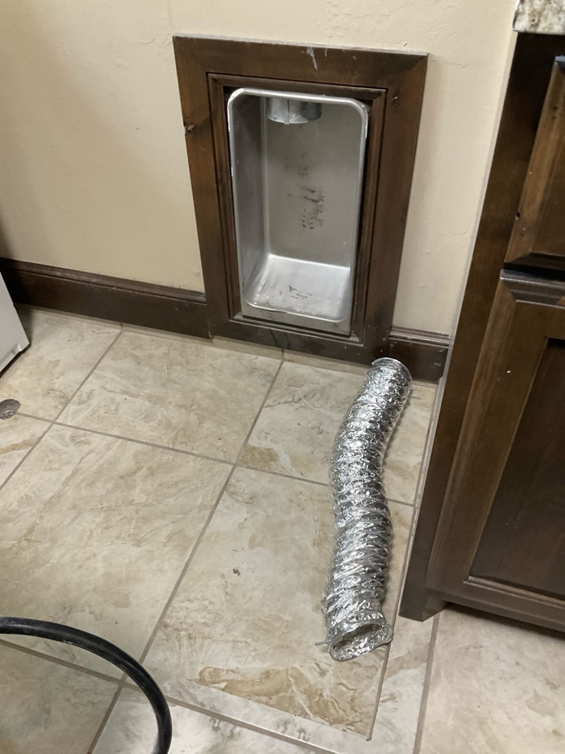 Silver flexible dryer vent duct on tile floor during inspection