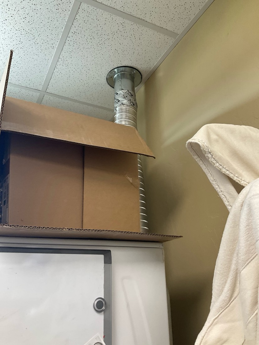 Installed dryer vent duct extending through ceiling with trim ring