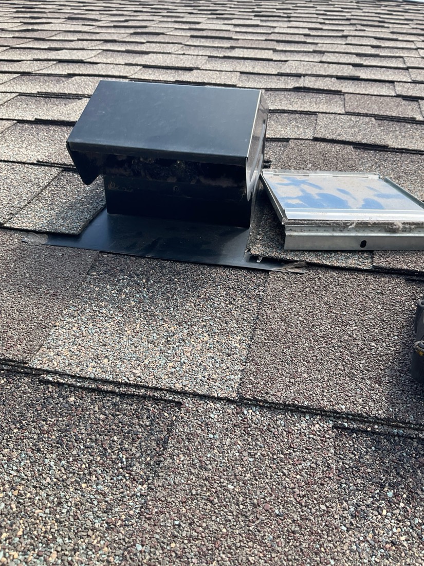 New black roof vent hood mounted on asphalt shingle roof.