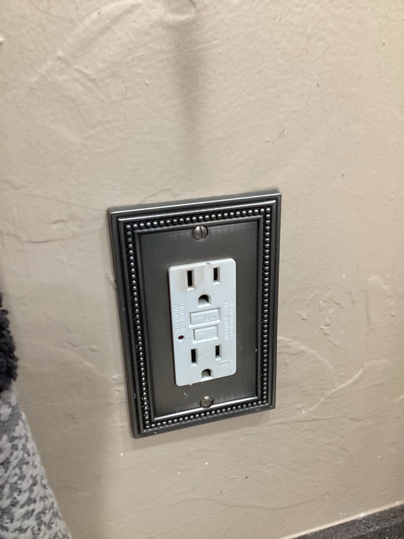 Newly installed GFCI outlet with black decorative cover plate.