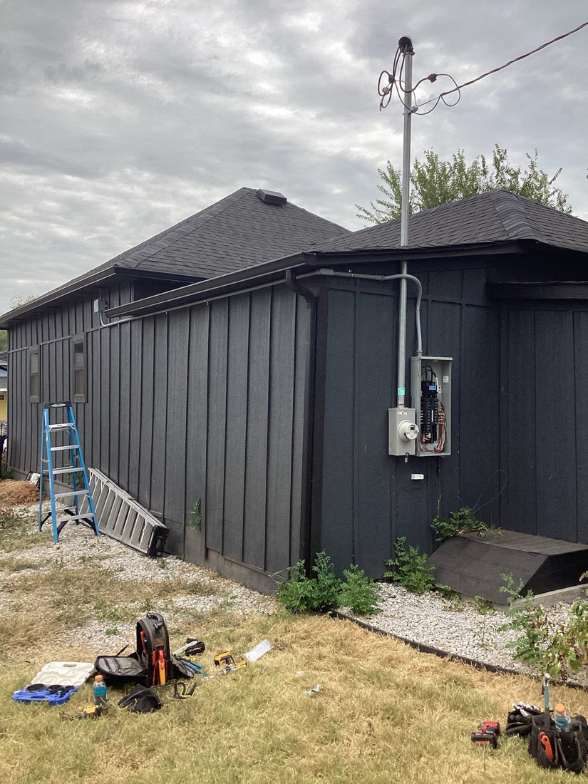 Exterior electrical installation with service panel and conduit on building.