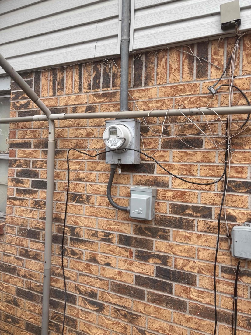 Newly installed electrical meter mounted on brick wall exterior