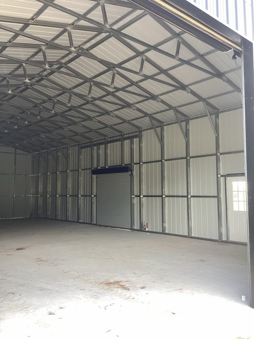 Metal building interior with white roller door and polished concrete floor.