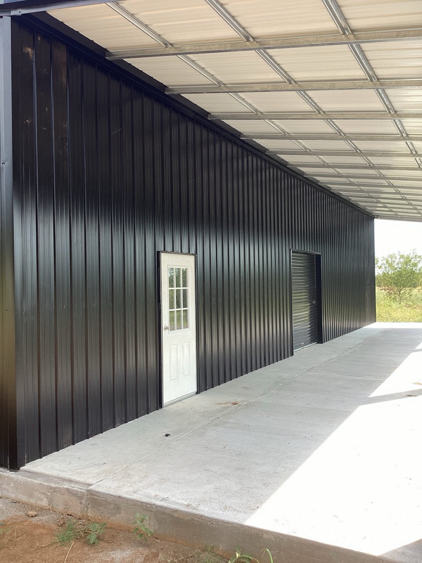 Metal frame building exterior with concrete slab and white door.