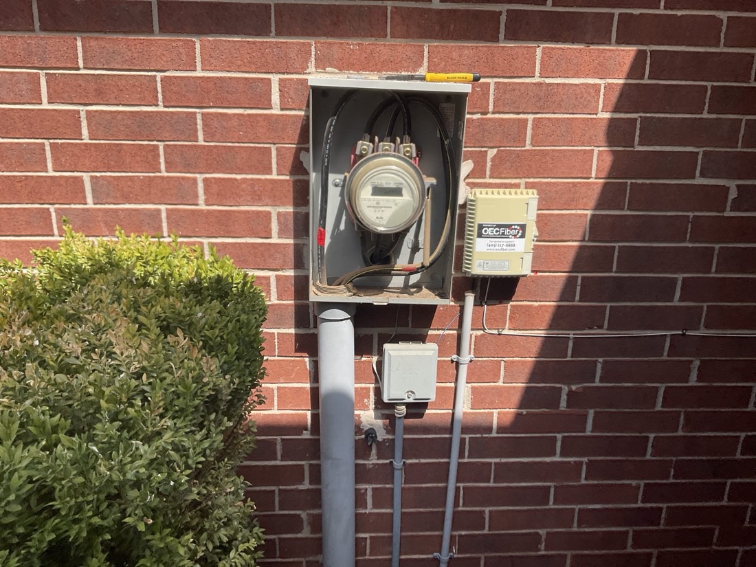 New digital meter mounted on red brick wall with conduit