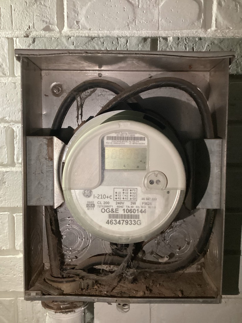 OG&E electric utility meter mounted in exterior weathered box.