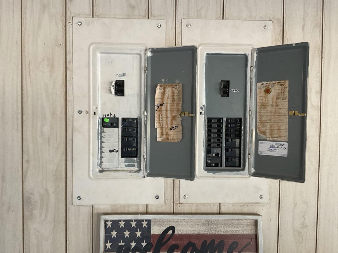 Four-panel electrical installation with disconnect switches and breaker boxes on wood.