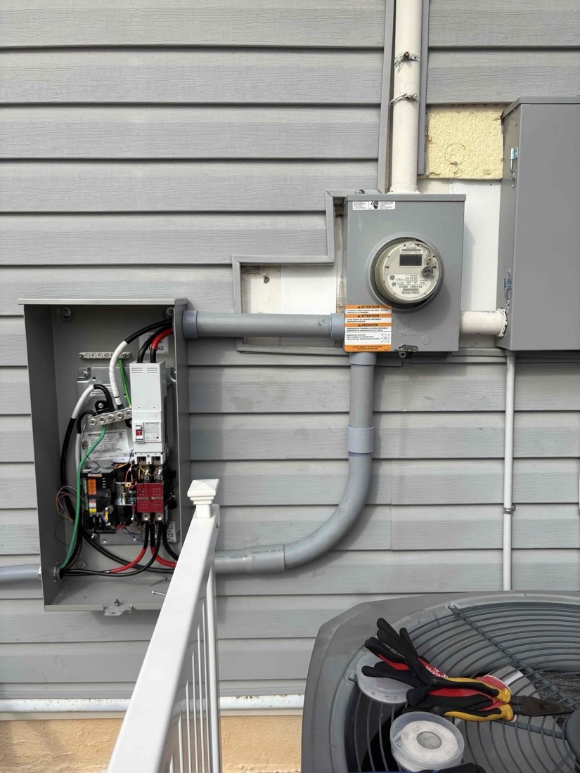 Exterior electrical installation with service panel, meter, and conduit wiring on house siding