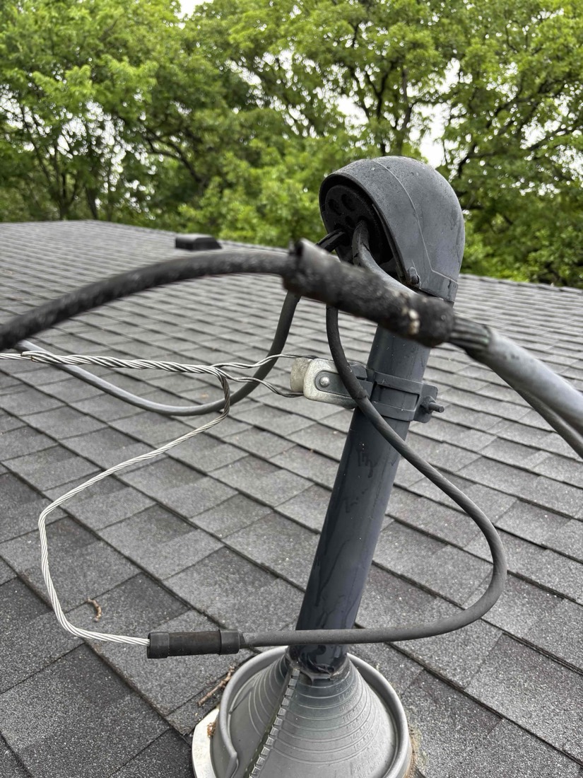 Electrical service head with protective cap and secured conduit on roof.