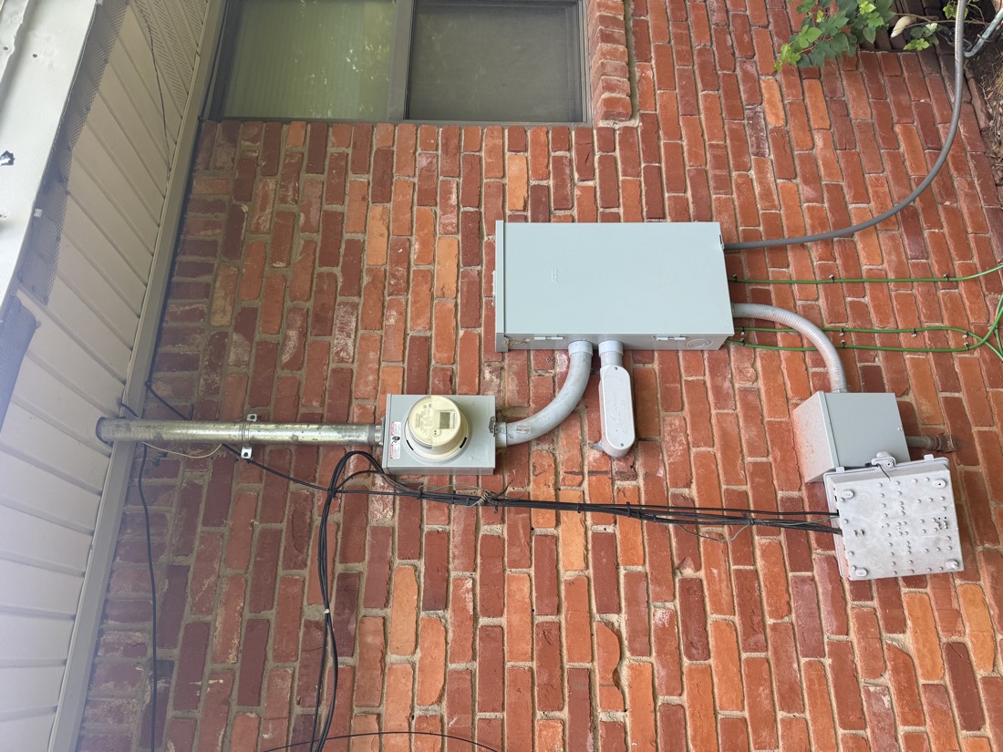 New electrical service panel with gray conduit on brick