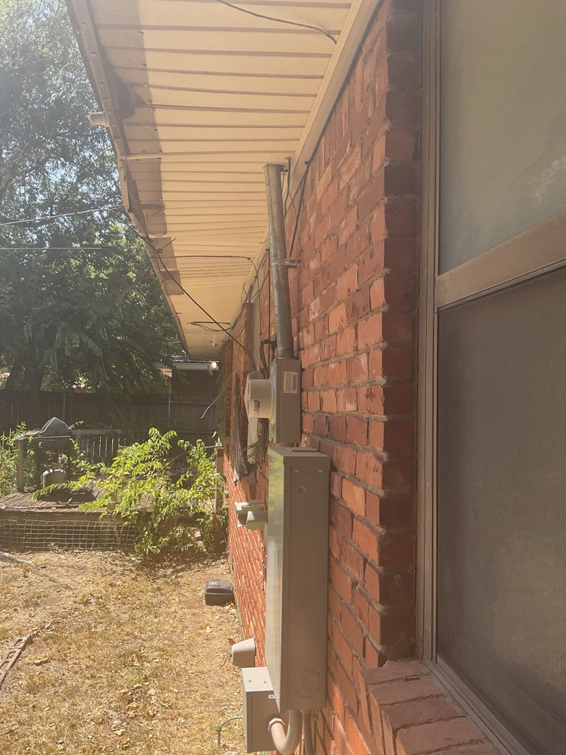 Exterior brick wall with new electrical conduit and service boxes installed.