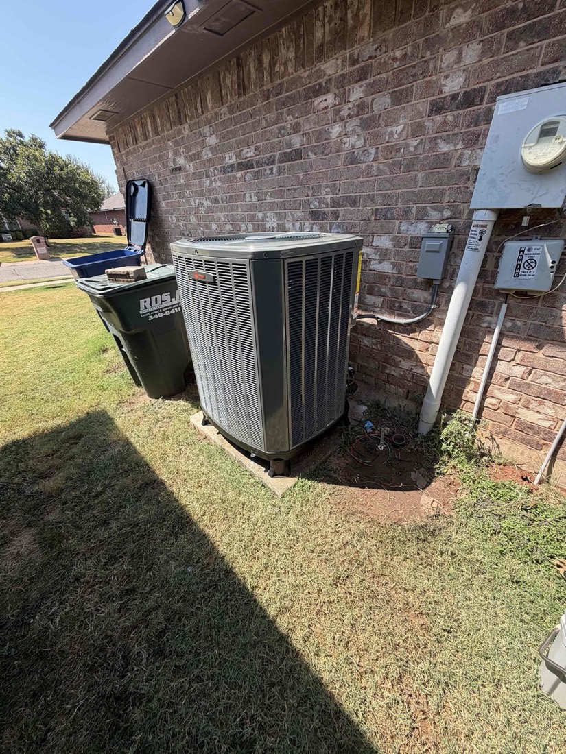 Installed air conditioning condenser unit on concrete pad near brick wall