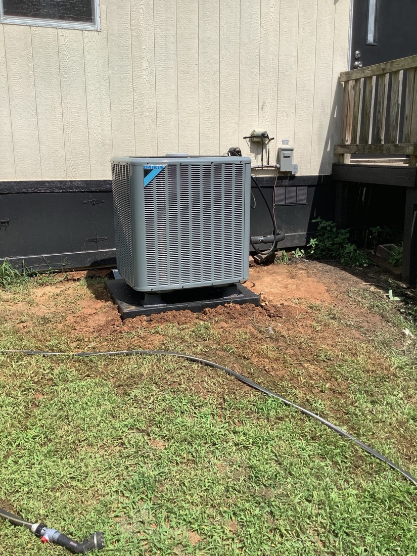 Newly installed Daikin AC condenser unit on ground pad outside residence