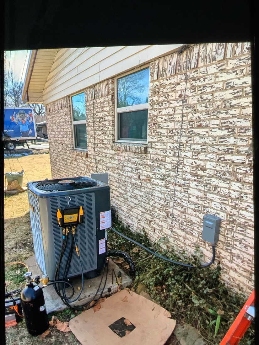 Installed AC condenser unit against brick home exterior.