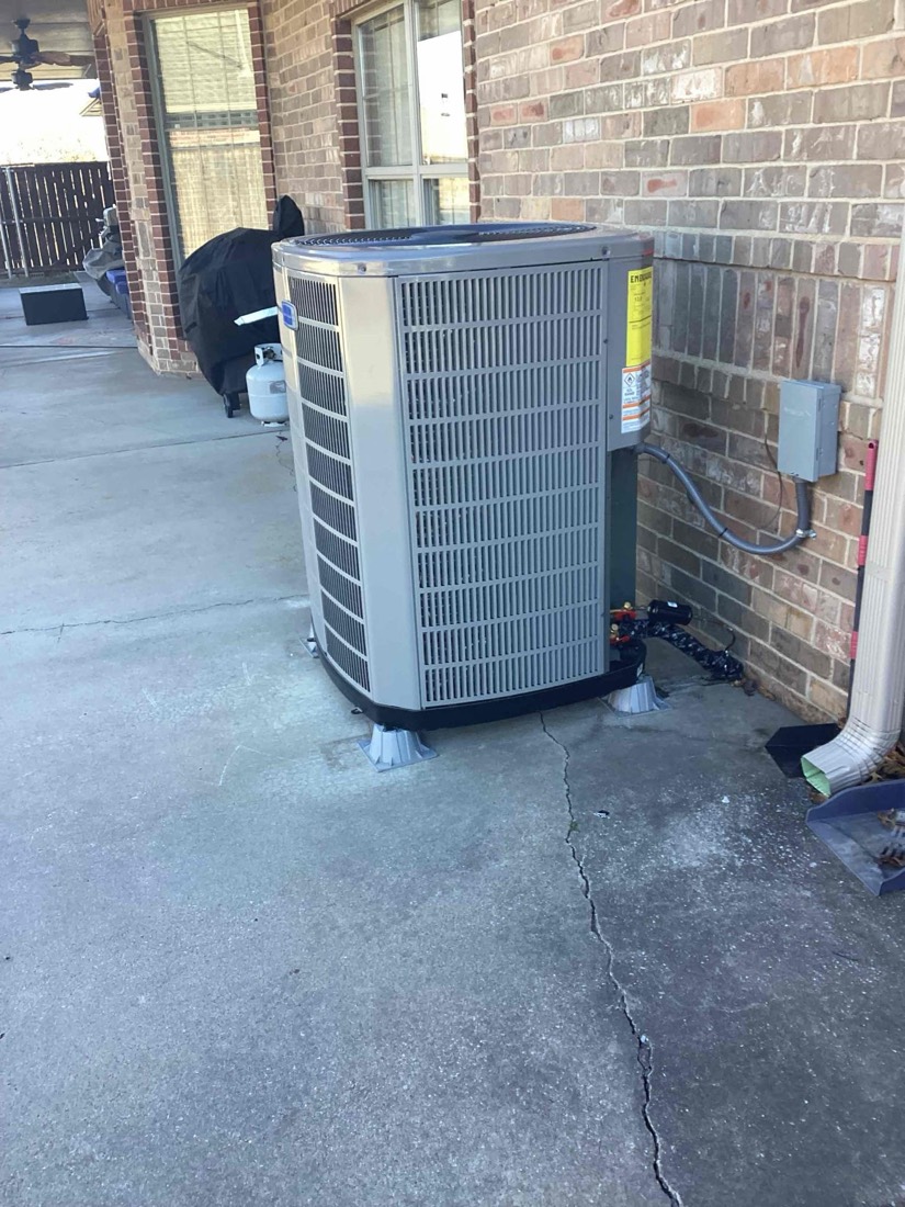New AC condenser unit installed outdoors on concrete pad during HVAC replacement.
