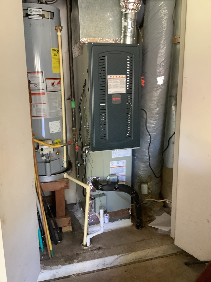Furnace and air handler unit installed indoors with ductwork and insulation.