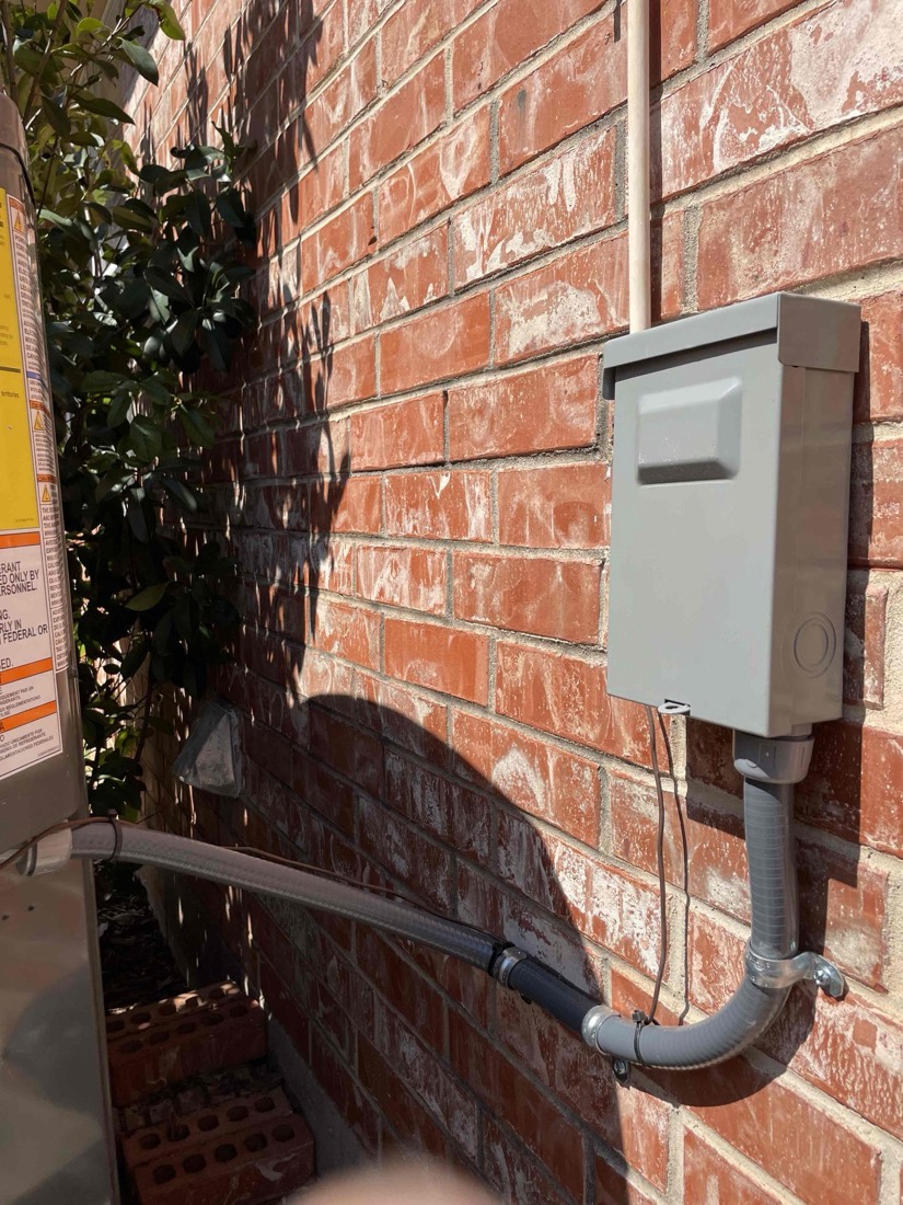 White electrical disconnect switch installed on brick wall.