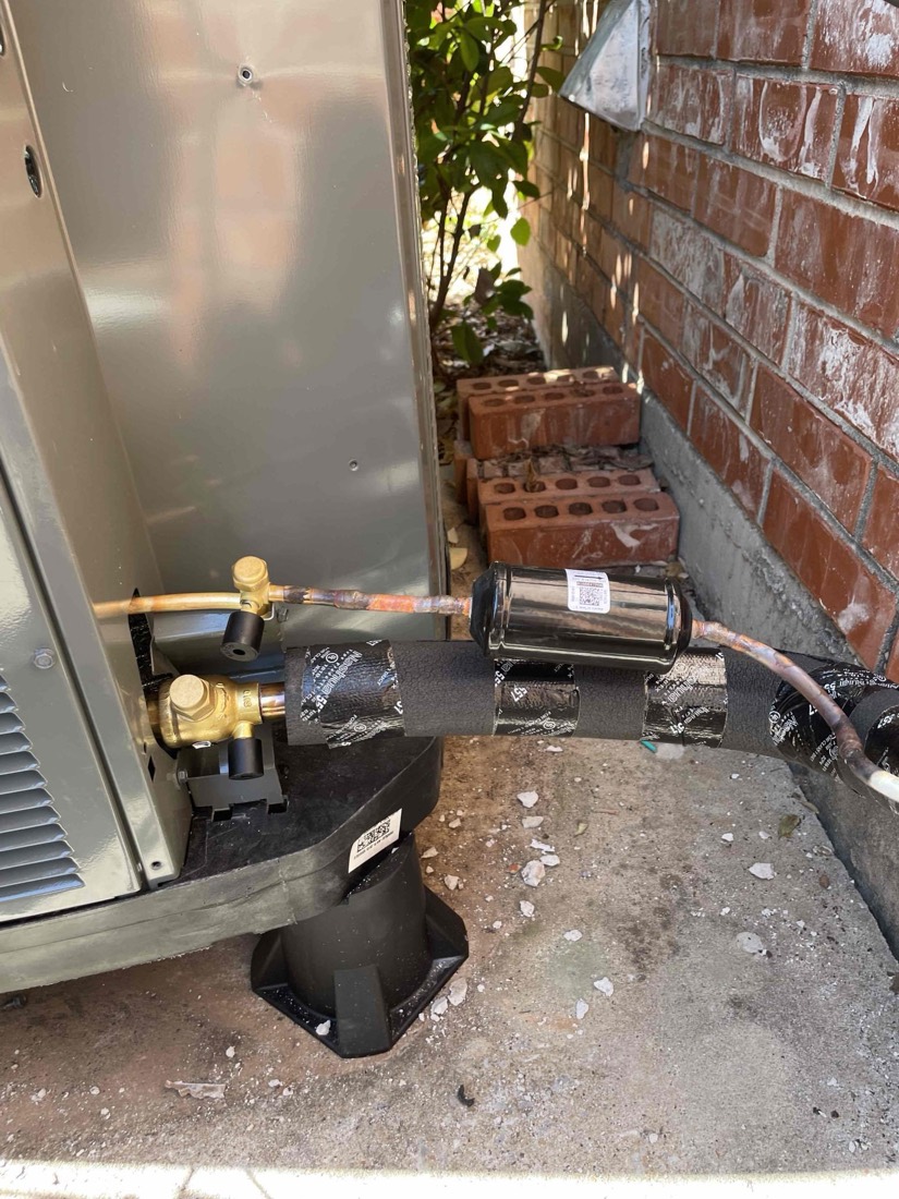 New AC unit installed in narrow side yard with piping and condensate drain.