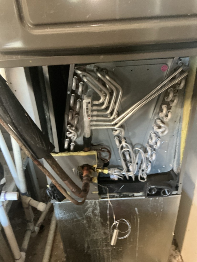 Evaporator coil with aluminum tubing and valve connections during AC installation.