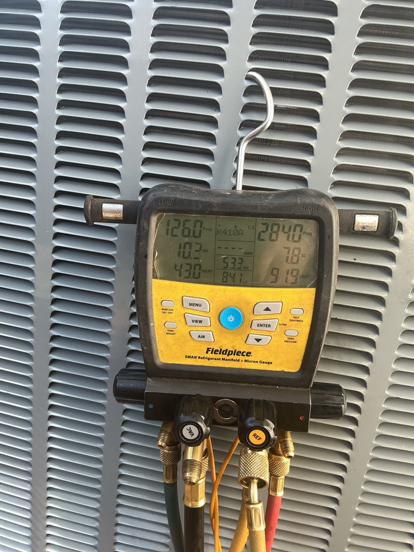 Digital manifold gauge showing refrigerant pressure readings on AC coil during installation.