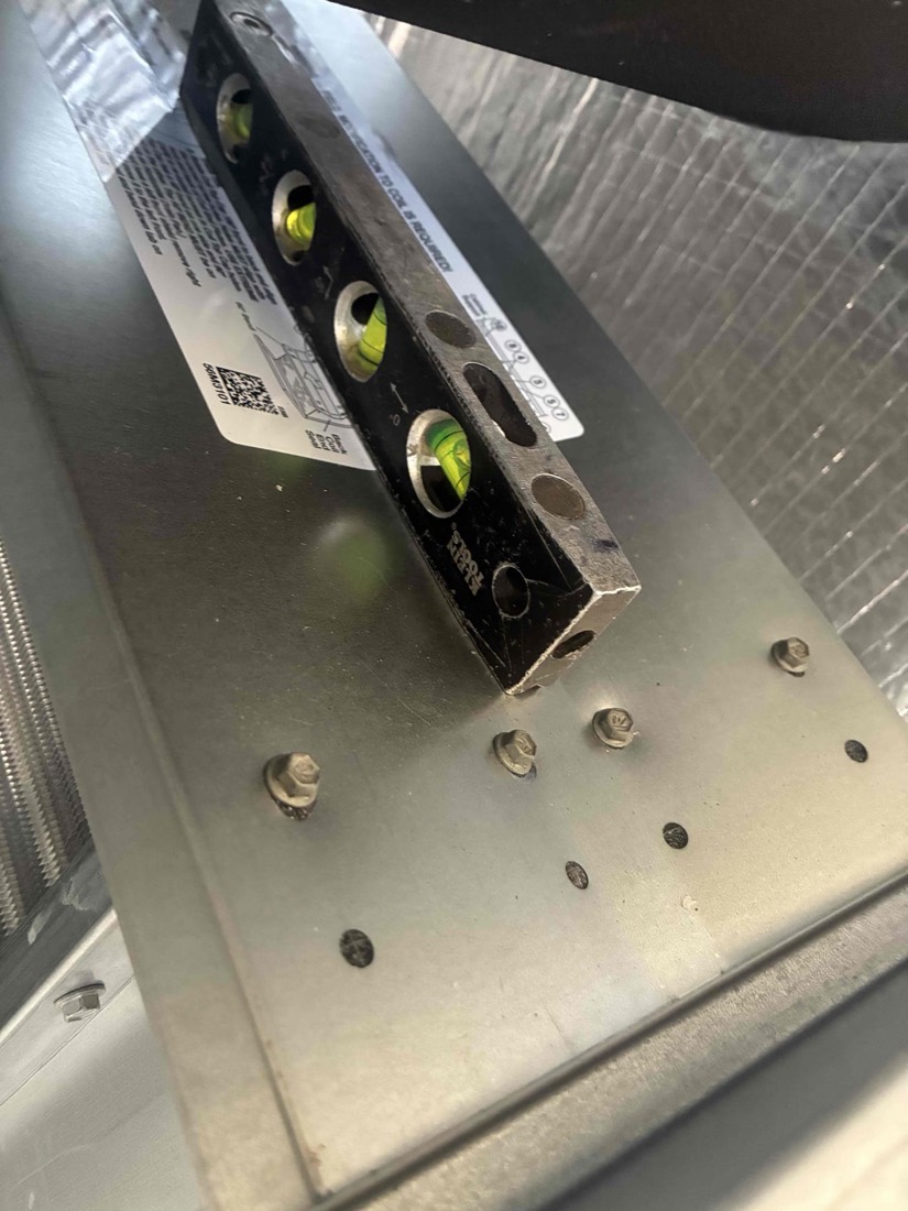 Spirit level on new HVAC condenser unit showing installation verification