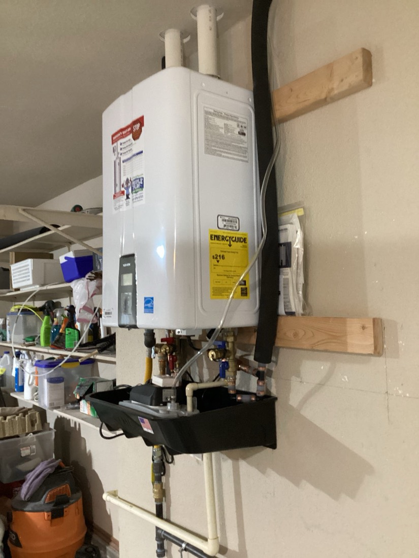 White tankless water heater mounted on wall with connections